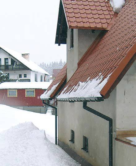 Fot. 3. Z metalowych (śliskich) pokryć dachów o dużym kącie nachylenia śnieg spada tuż po opadach. Na ziemi pod okapem widać sporą górę śniegu, który nie może utrzymać się na dachu, i rynny są całe, mimo że są wystające.