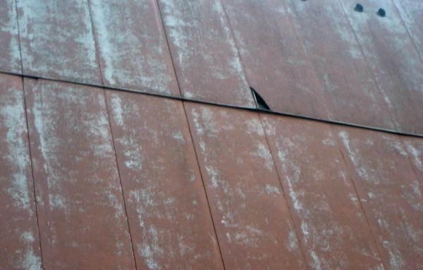 Fot. 10. Uszkodzenia mechaniczne płyt azbestowych osłaniających izolację z wełny mineralnej na szczytach budynku