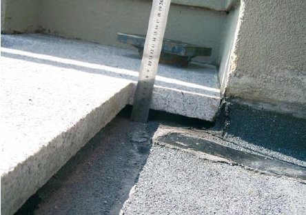 FOT. 1. Dach tarasowy wyłożony płytami granitowymi z hydroizolacją z papy ułożonej na szlichcie ze spadkiem. Widać niezbyt fortunny sposób zamocowania papy na attyce: papę do ocieplonego muru attyk dociskają płyty. Woda na pewno spenetruje to połączenie