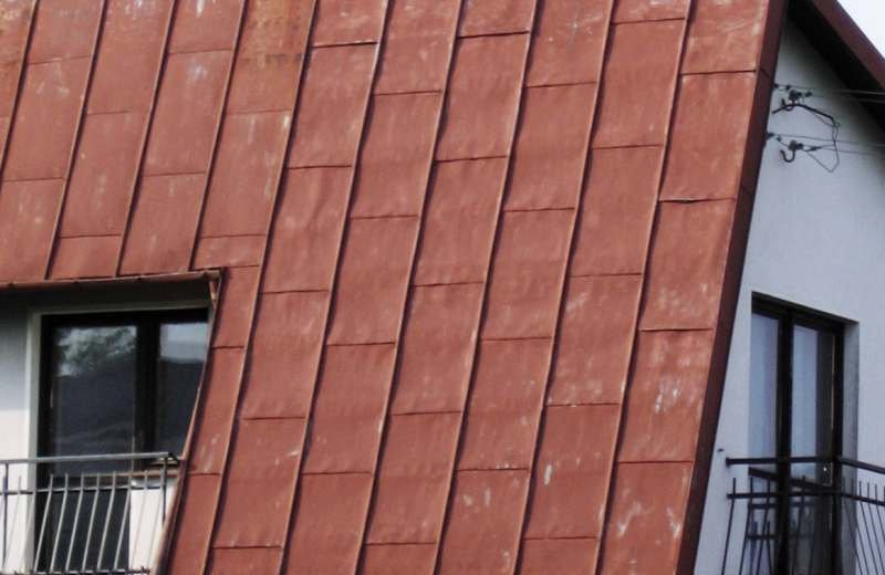 FOT. 1. Duży kąt nachylenia (70°) tej połaci oraz jej usytuowanie na zachodniej stronie budynku spowodowało, że przez wiele lat eksploatacji, blacha została wgięta odwzorowując deski, do których jest zamocowana. Powinna być ułożona na poszyciu.